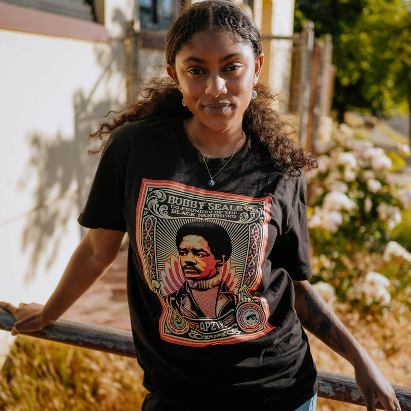 Female model wearing Large illustrated graphic by Shepard Fairey, founder of Black Panthers on a black t-shirt .