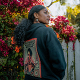 Back angle of female model wearing Educate to Liberate black hoodie outdoors.