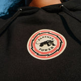Detailed close shot of female model wearing Educate to Liberate black hoodie with Panther power emblem at front center.