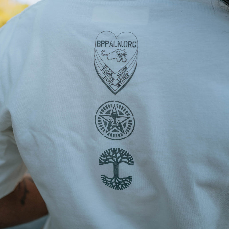 Close-up of three logo marks on model - Oaklandish, Panther Power & BPLAN on the backside of a natural colored limited edition t-shirt.
