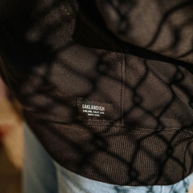 Detailed close up of Collector's edition premium black hoodie with Oaklandish woven label tag on front pocket.