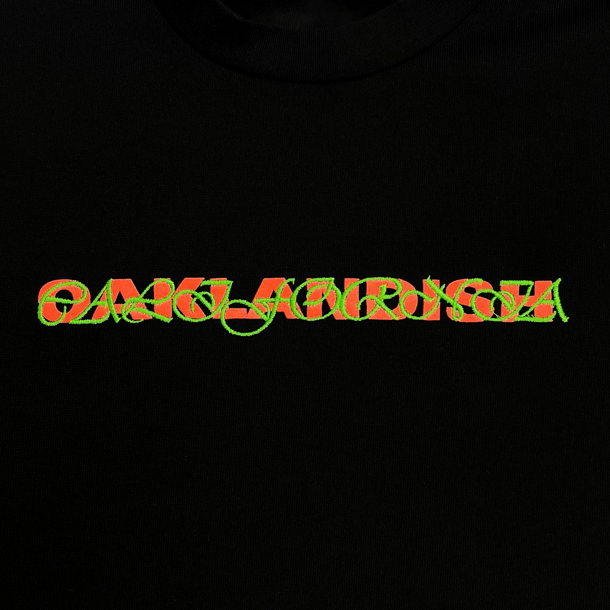 Close-up on Oaklandish wordmark with green scripted Oaklandish wordmark on top on a black t-shirt.