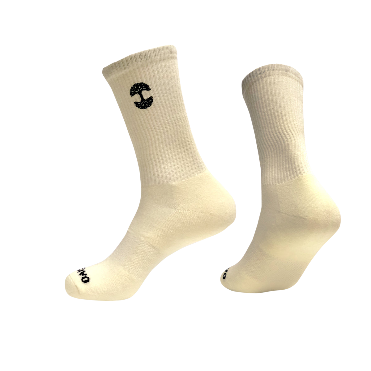 Two off-white cotton crew socks with black logos are suspended mid-air against a white background. The Oaklandish Embroidered Logo Socks are ribbed on the calf area, with one displaying an embroidered stylized "C" near the top and the other sporting a small circular logo on the toe. The overall design is minimalistic and clean.