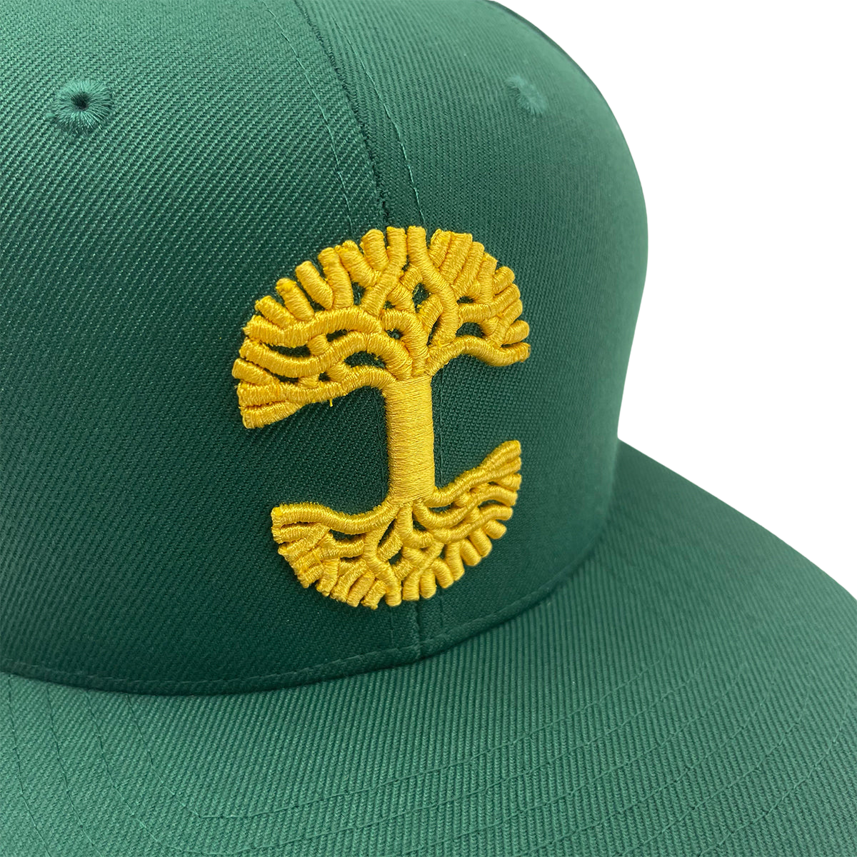 The Oaklandish Classic Snapback by Oaklandish is a green baseball cap with a yellow embroidered design on the front, resembling a tree with a stylized trunk and branches forming circular patterns at the top and bottom, reminiscent of the Oaklandish logo. This snapback cap features a flat bill with visible stitching along the seams.