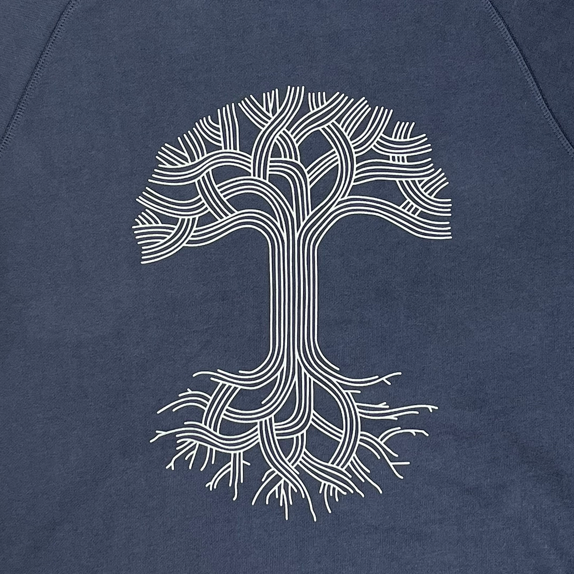 The Oaklandish Classic Premium Hoodie by Oaklandish features a minimalist white line art tree design centered on a dark blue fabric background. The tree showcases intertwined branches and roots in a symmetrical pattern, with smooth curves and simple lines that create a stylized and modern appearance on this 100% cotton French Terry premium pullover hoodie.