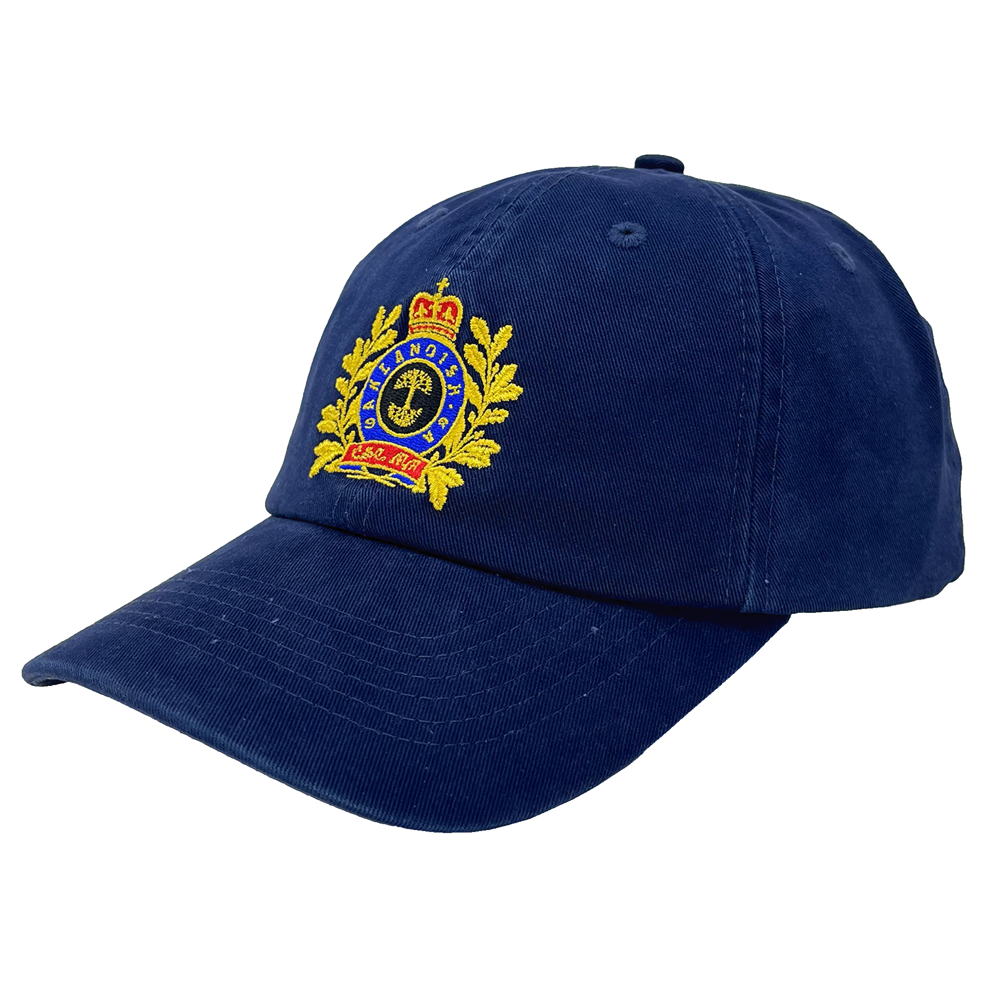 The Regal Crest Dad Hat by Oaklandish is a navy blue, 100% cotton hat with a detailed embroidered emblem on the front. The emblem features a golden crown at the top, a circular design with text below, and laurel leaves on either side. The visor is slightly curved and there’s an adjustable strap at the back for a perfect fit.