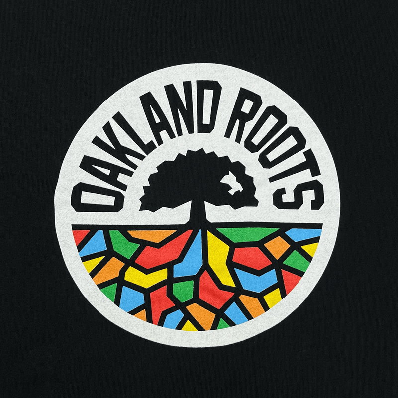 Detailed close-up of full color Oakland Roots circle mosiac tree logo on the back of a black hoodie.