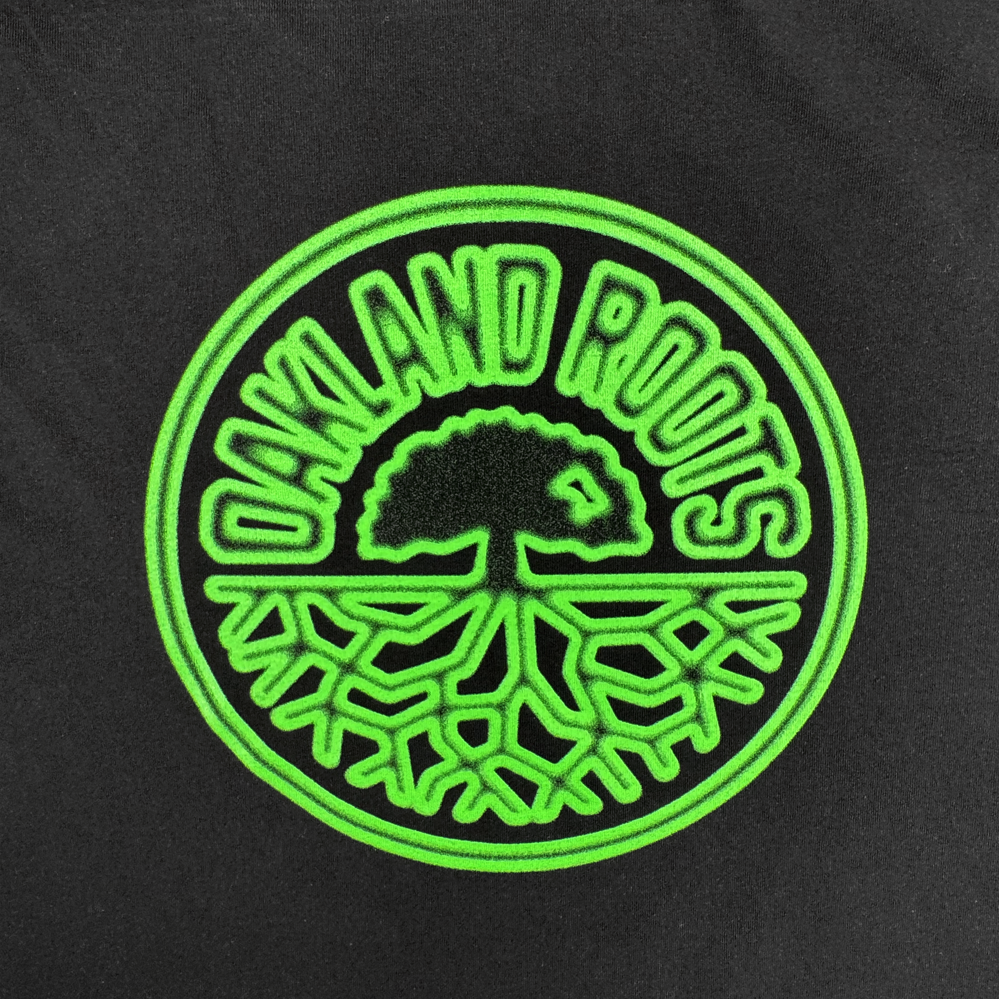 The Acid Tee by Oakland Roots SC features a circular neon green logo on black with a tree and roots, "OAKLAND ROOTS" arched above—capturing the spirit of Roots SC and perfect for any Oakland-inspired design.