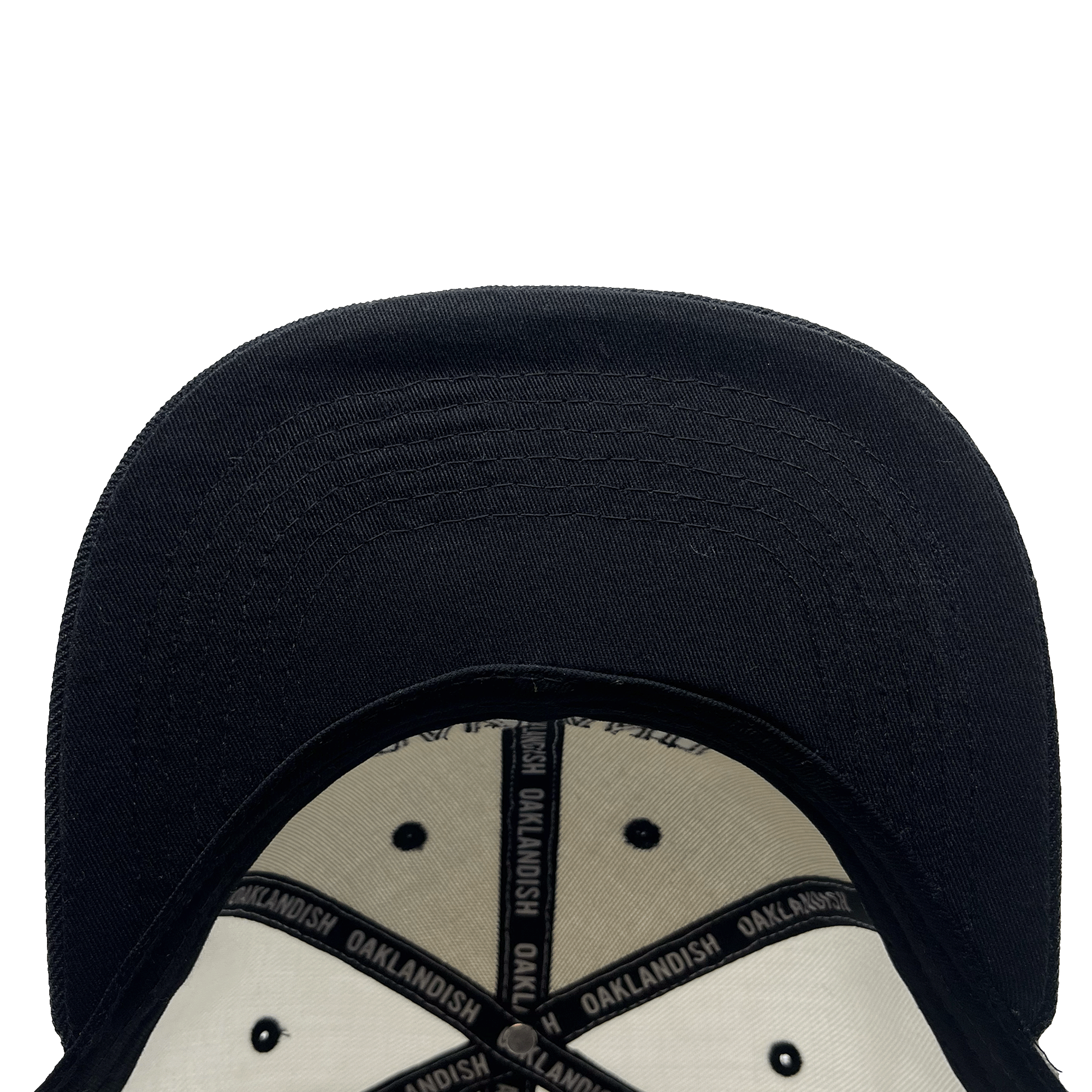 An underside view of the Oakland Roots SC Arched Text Snapback. The interior is lined with cream-colored fabric and accented by black stitching, along with a black band that repeatedly reads "OAKLANDISH." The cap's brim is prominently visible, displaying detailed stitching. The background is plain and white.