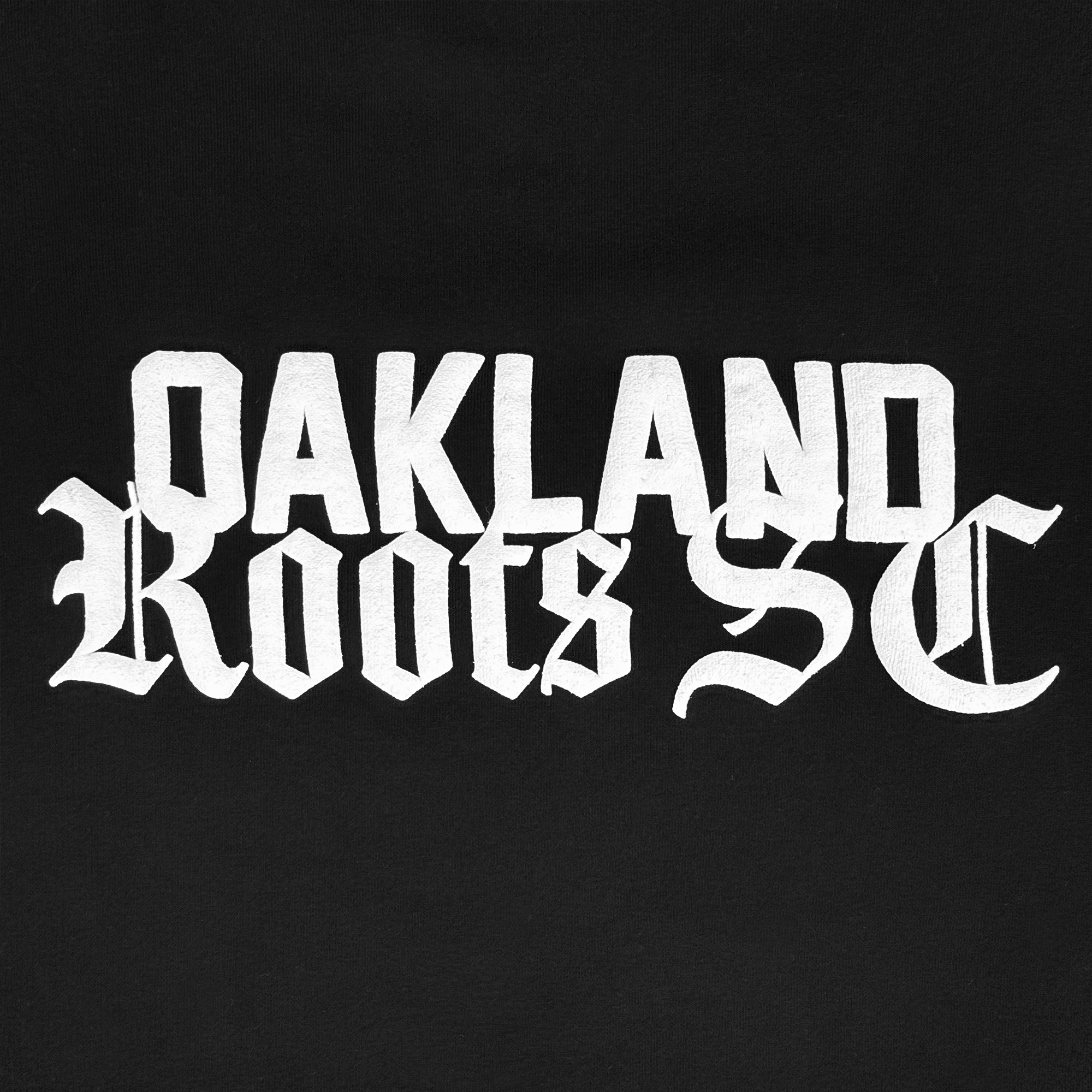 White, bold, gothic-style text displays "OAKLAND Roots SC" on this solid black Oakland Roots SC Logo Premium Hoodie, with sharp, angular lettering and distinctive serifs for a striking and classic look.