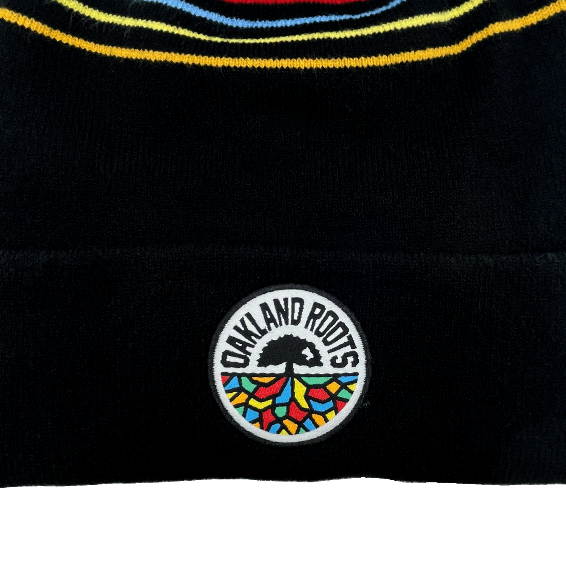 Close-up of Oakland Roots SC circle logo on the rolled cuff and colored stripes on the crown of a black pom hat.