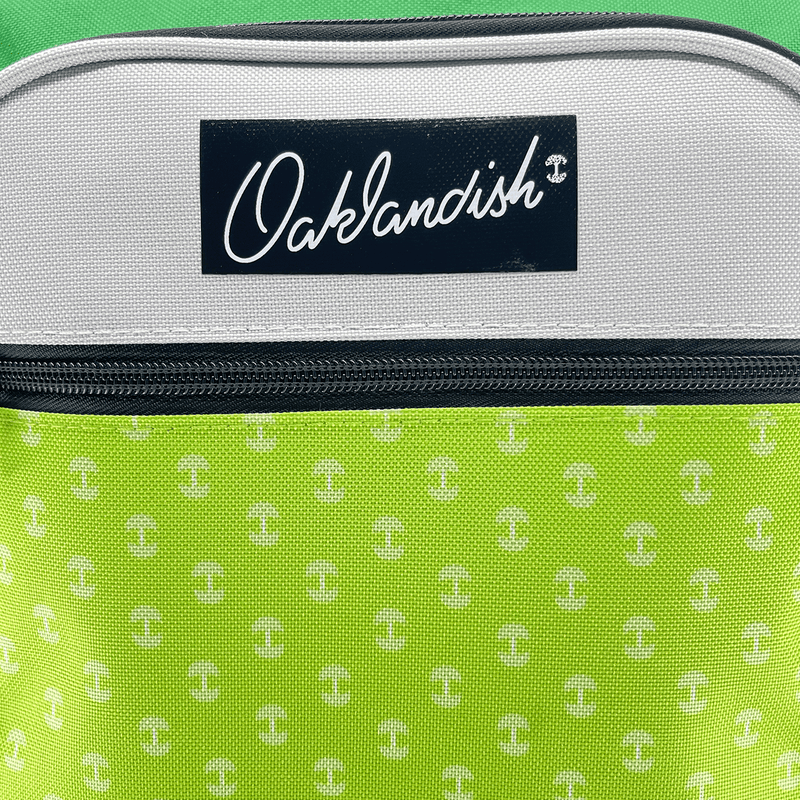 Close-up of black Oaklandish logo patch on the front pouch of a green and grey primary school back pack.