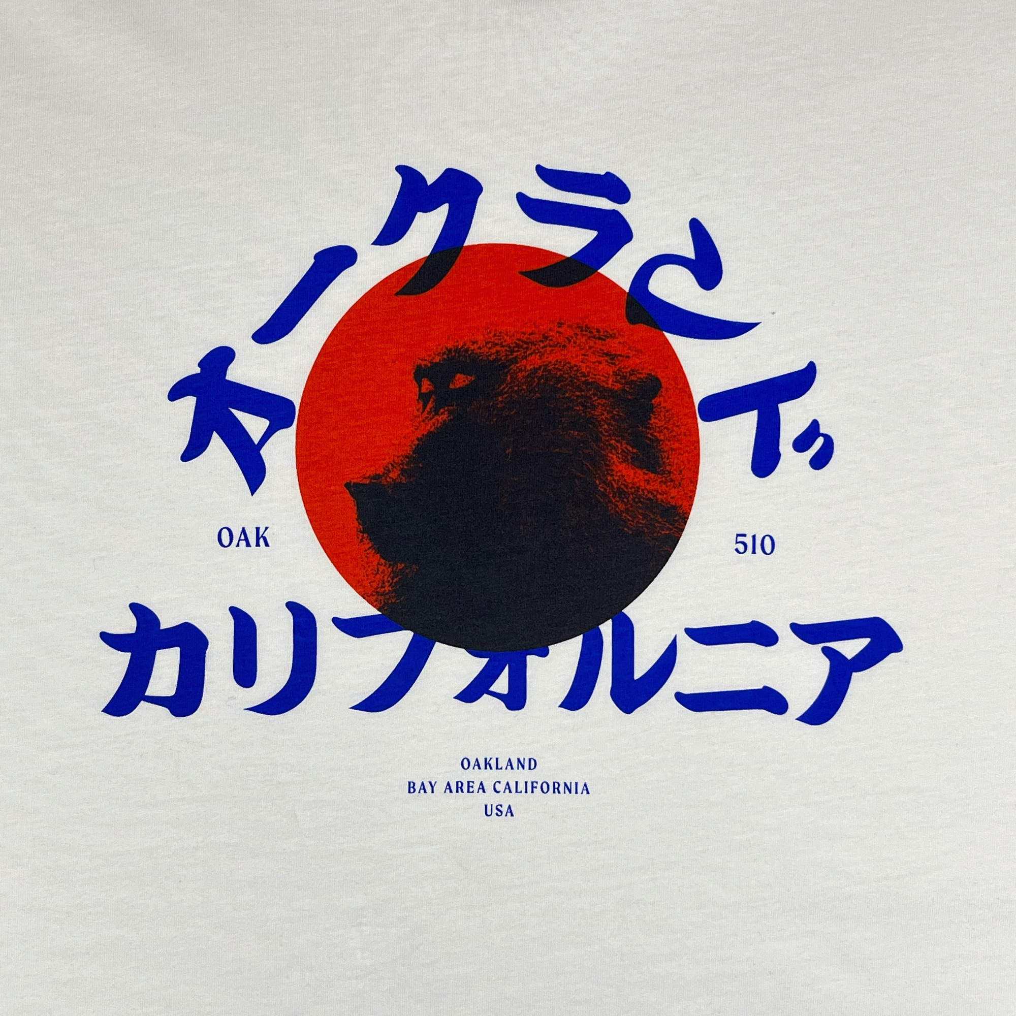 Close-up of snow monkey graphic with Asian written characters, Oak 510 wordmark & Oakland Bay Area California wordmark on white t-shirt.