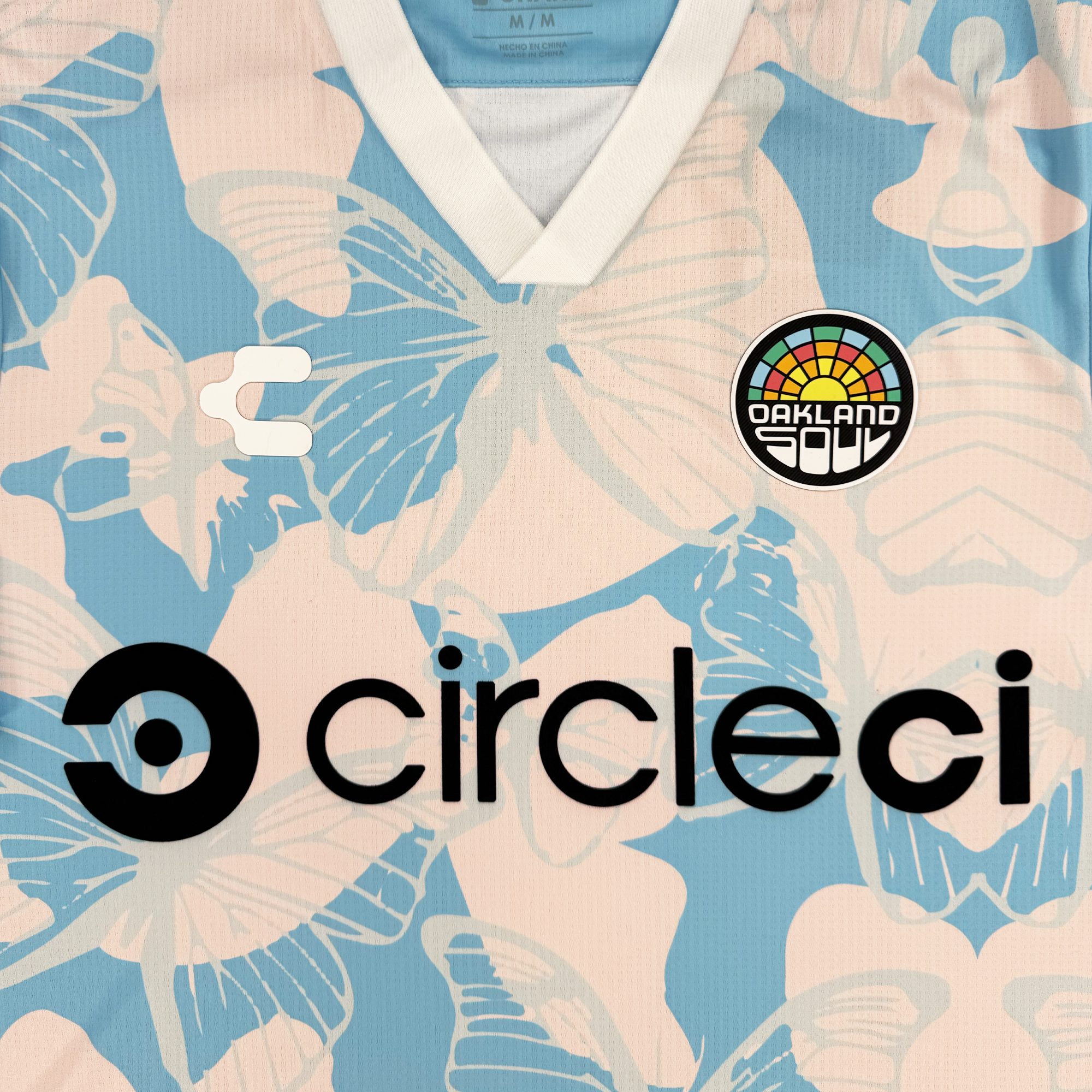 The Oakland Soul Custom Unisex Butterfly Effect Kit features a pale pink and blue butterfly and floral tie-dye design, white V-neck collar, Charly logo on the right, Oakland Soul badge on the left, and bold black "circleci" sponsor across the chest.