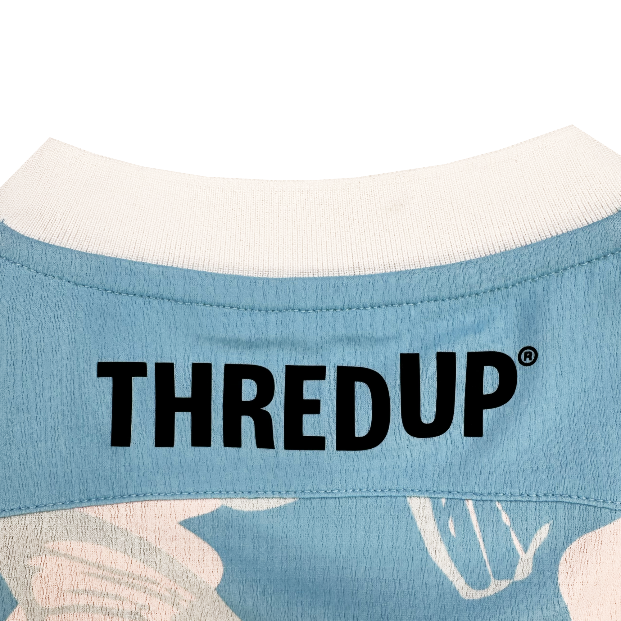 Close-up of the upper back of a light blue shirt from Oakland Soul’s Custom Butterfly Effect Kit, featuring a white collar and subtle floral tie-dye patterns that showcase creative Oakland style. "THREDUP" is printed in bold black letters.