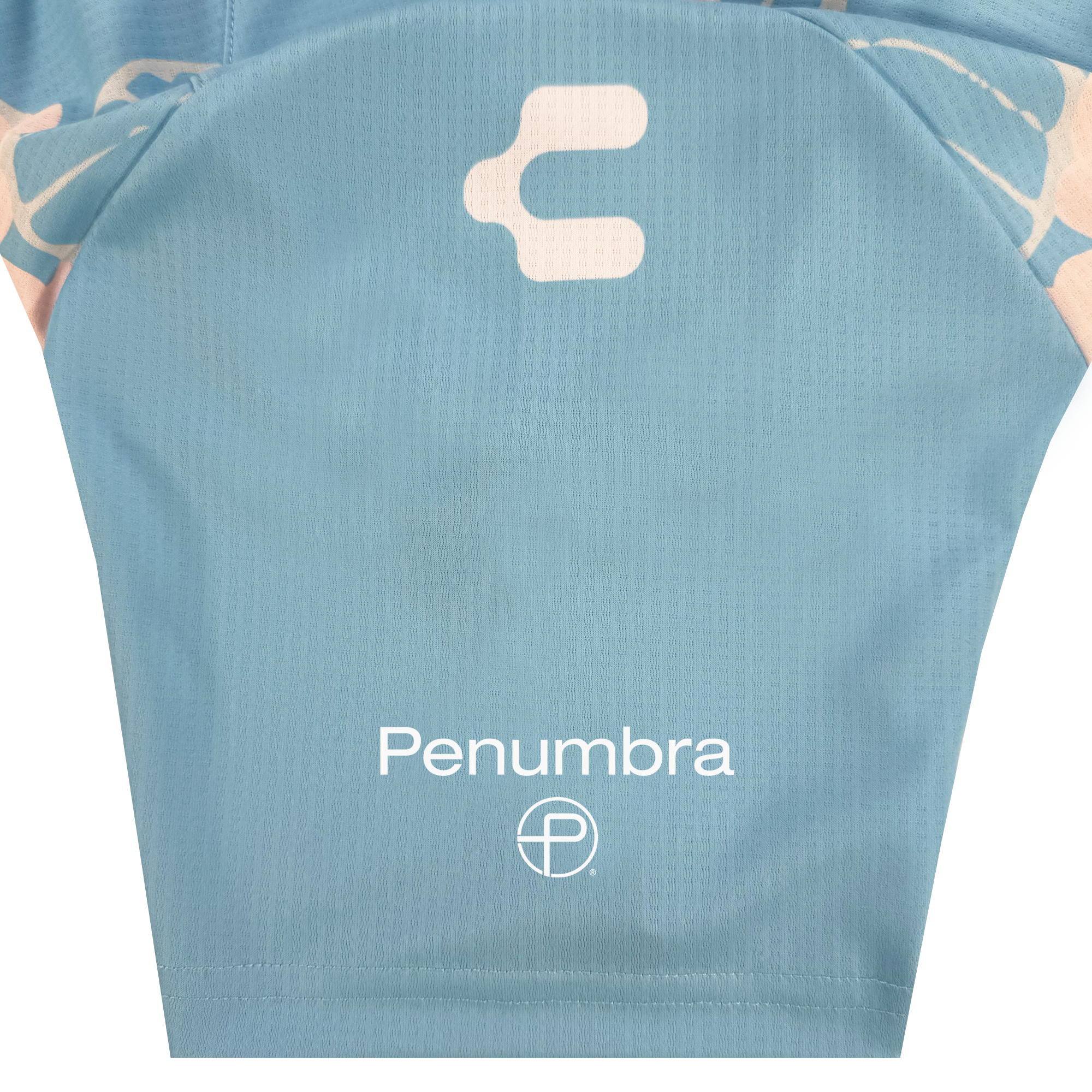 A close-up of a light blue Oakland Soul Custom Butterfly Effect Kit jersey sleeve with "Penumbra" and a circular logo in white, plus an abstract symbol above. The textured fabric shows pale pink and white floral tie-dye at the edges.