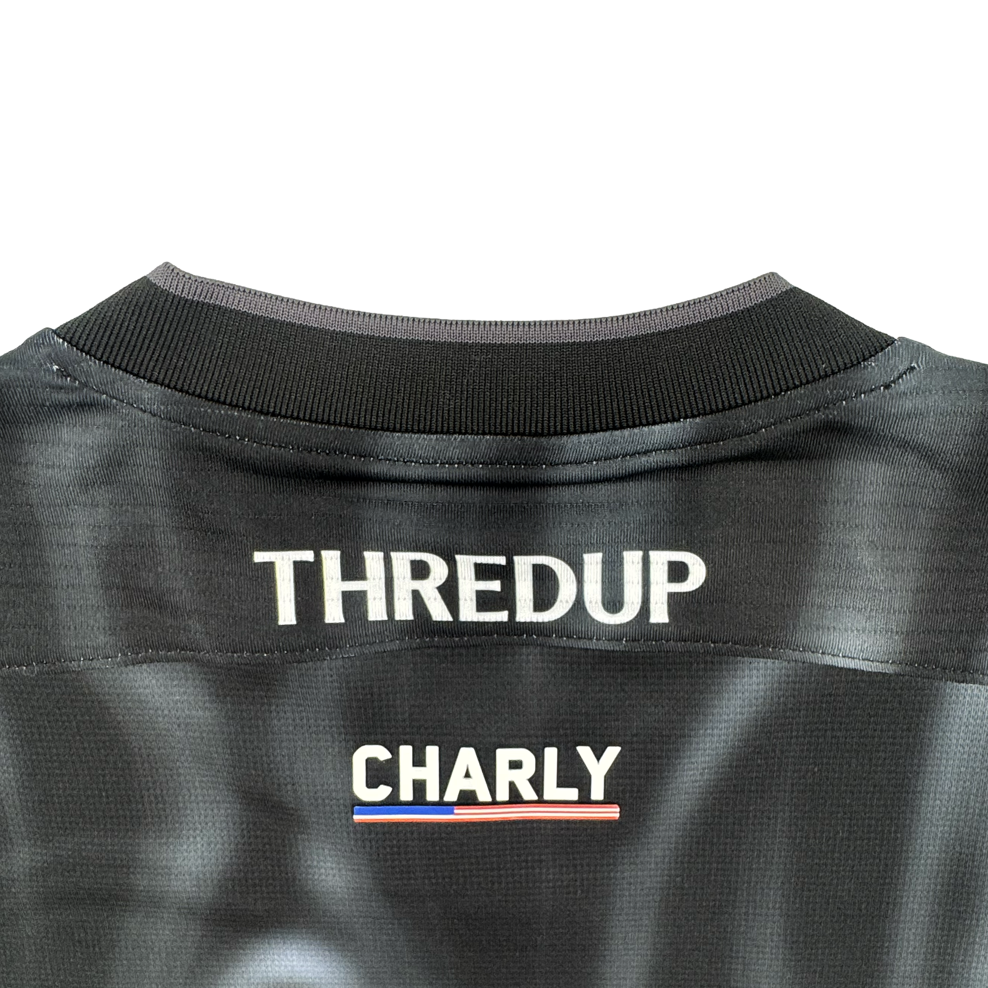 A close-up of the 2026 Oakland Soul SC Spirit Jersey by Oakland Soul, featuring "THREDUP" in bold white letters with a red, white, and blue underline. The black collar has gray trim, and the polyester fabric displays a subtle pattern.