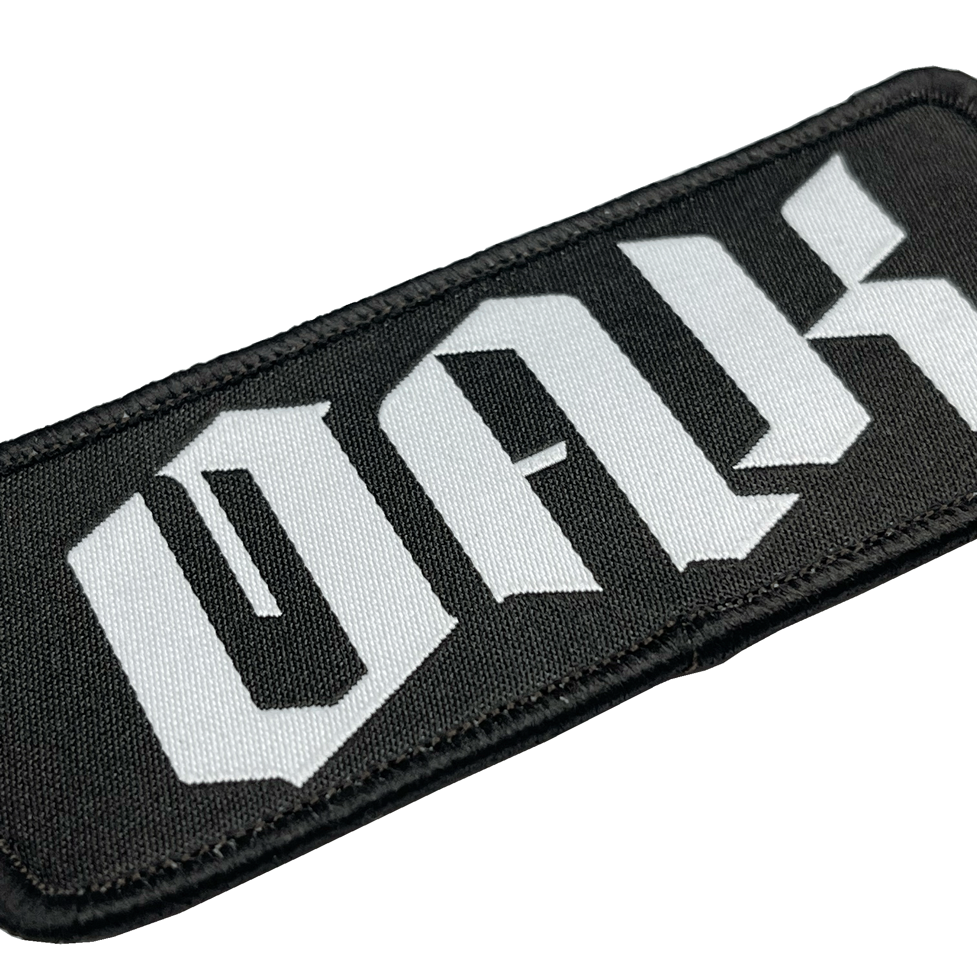 Close-up of woven black iron-on patch with white OAK wordmark in drip.