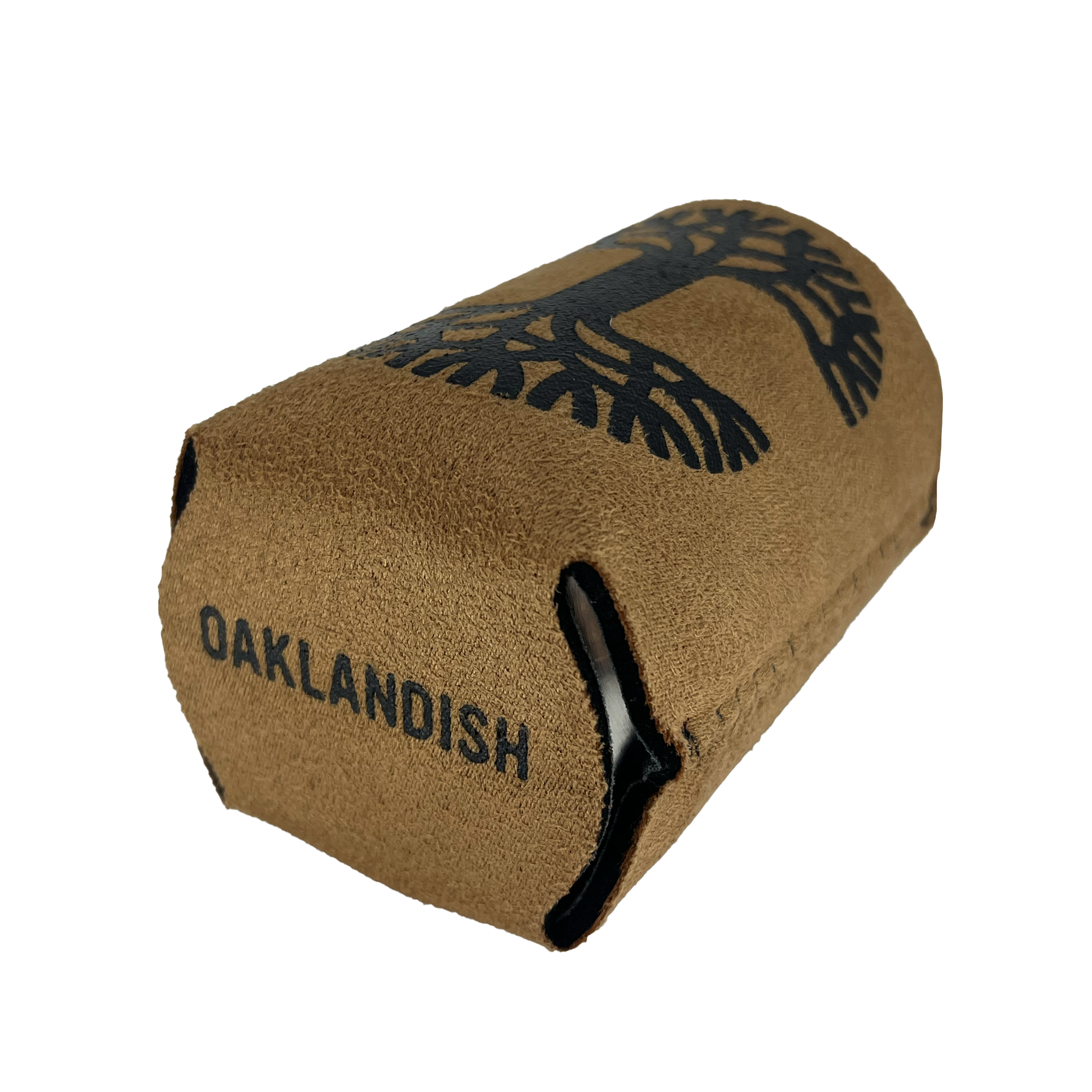 The Oaklandish Suede-ish Can Cooler is a brown can koozie branded with "OAKLANDISH" printed in black and accented by a black tree design above the text. The collapsible drink insulator sleeve, made of neoprene-like material, is positioned horizontally with its opening facing the left side of the image.