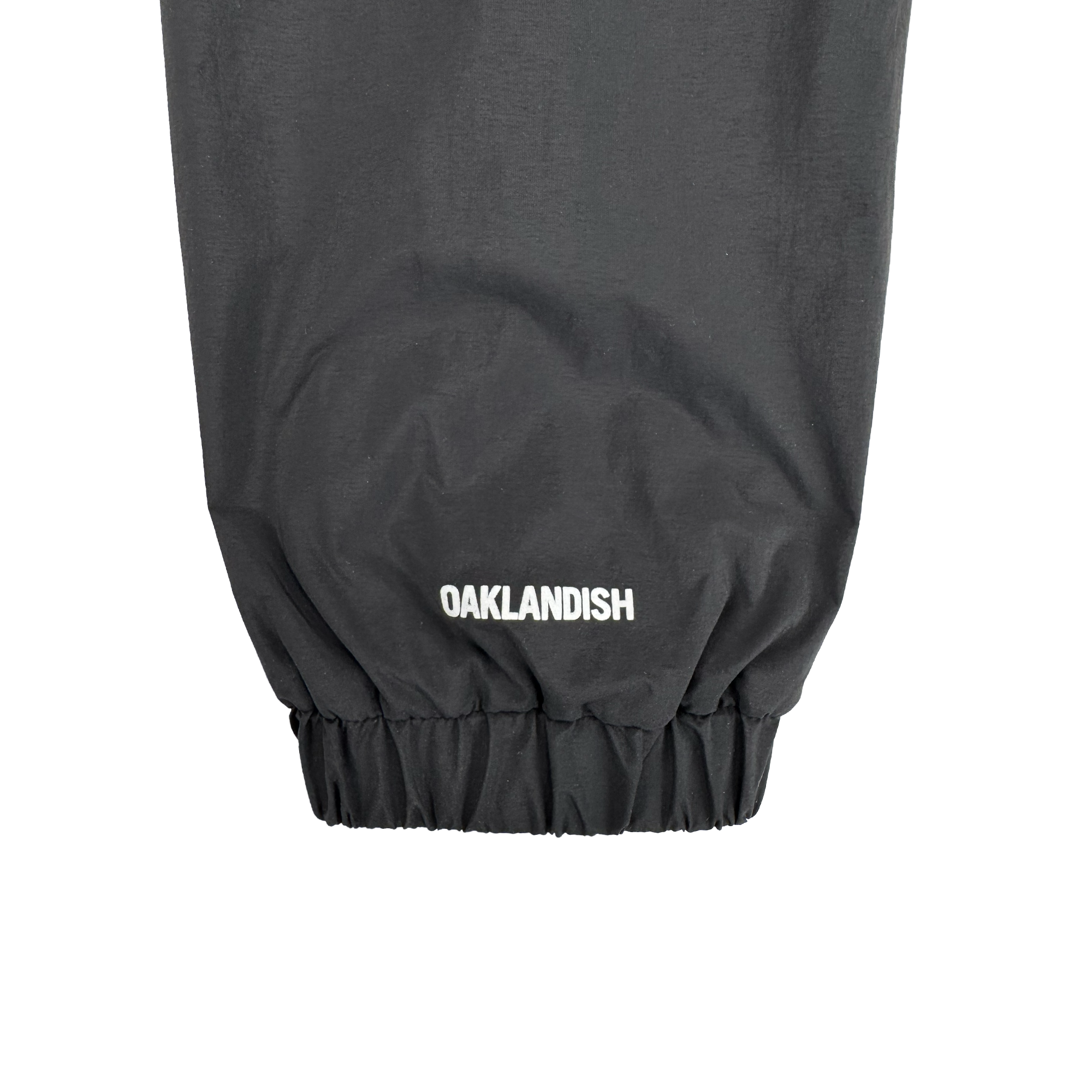 Close-up of the Susurrus Track Top's black sleeve with an elastic cuff. "Oaklandish" is boldly printed in white near the cuff, highlighting the brand on this men's zip jacket.