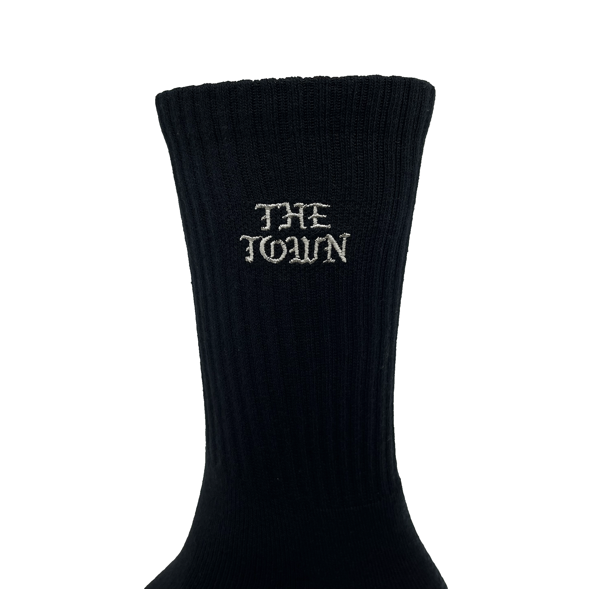 Close-up of embroidered white THE TOWN wordmark in Old Town English on the calves of black crew socks.