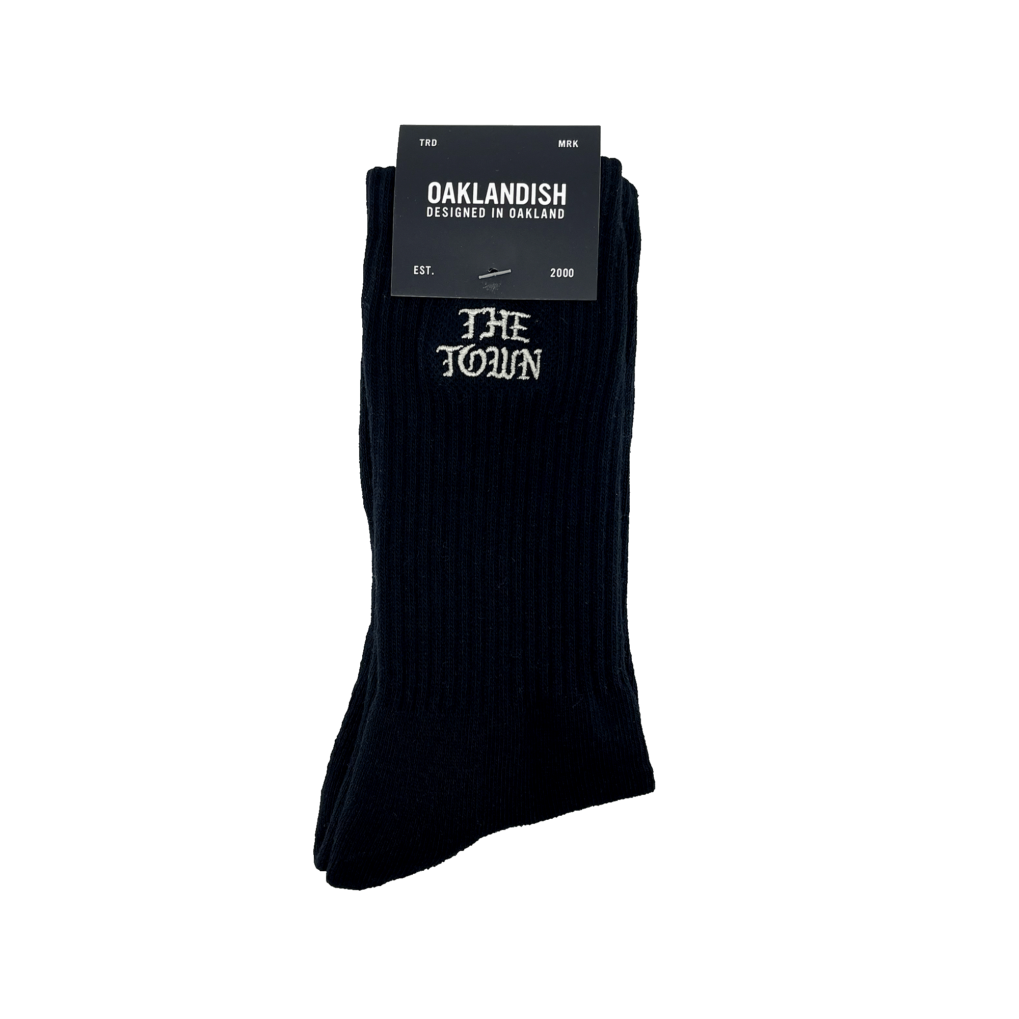 The Town Old English Sock, designed by Oaklandish, is a pair of black crew socks featuring "THE TOWN" embroidered in white lettering near the top. The packaging includes a black label with "OAKLANDISH DESIGNED IN OAKLAND," the Nike logo, and additional text stating "FOR MEN," "ONE SIZE FITS MOST," and "EST. 2000.