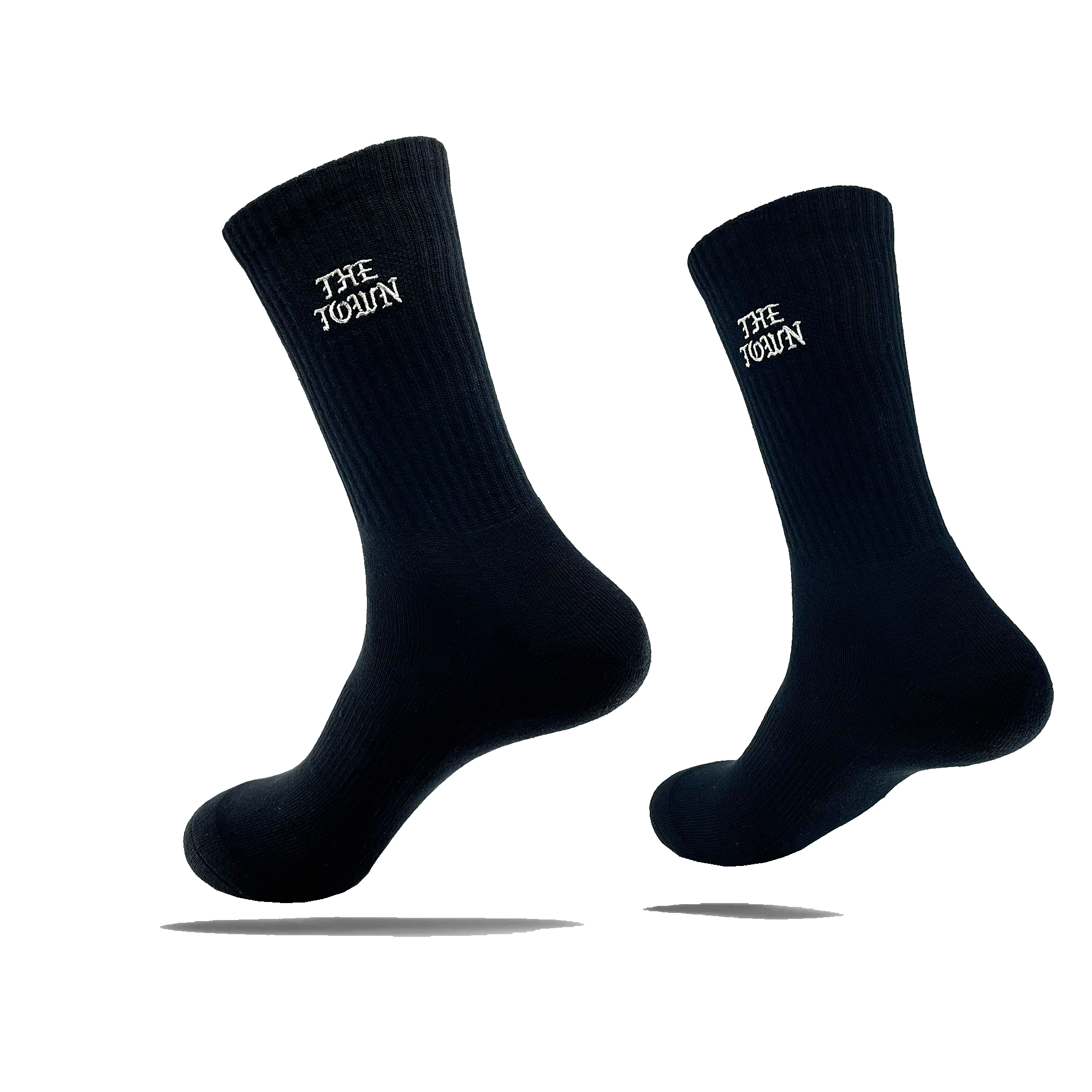 Image of two black crew socks, each showcasing the white text "THE TOWEL" near the top. These stylish crew socks, named The Town Old English Sock by Oaklandish, are one size fits most and appear to be floating against a transparent background, casting a shadow beneath each sock. The material features a ribbed texture at the top.