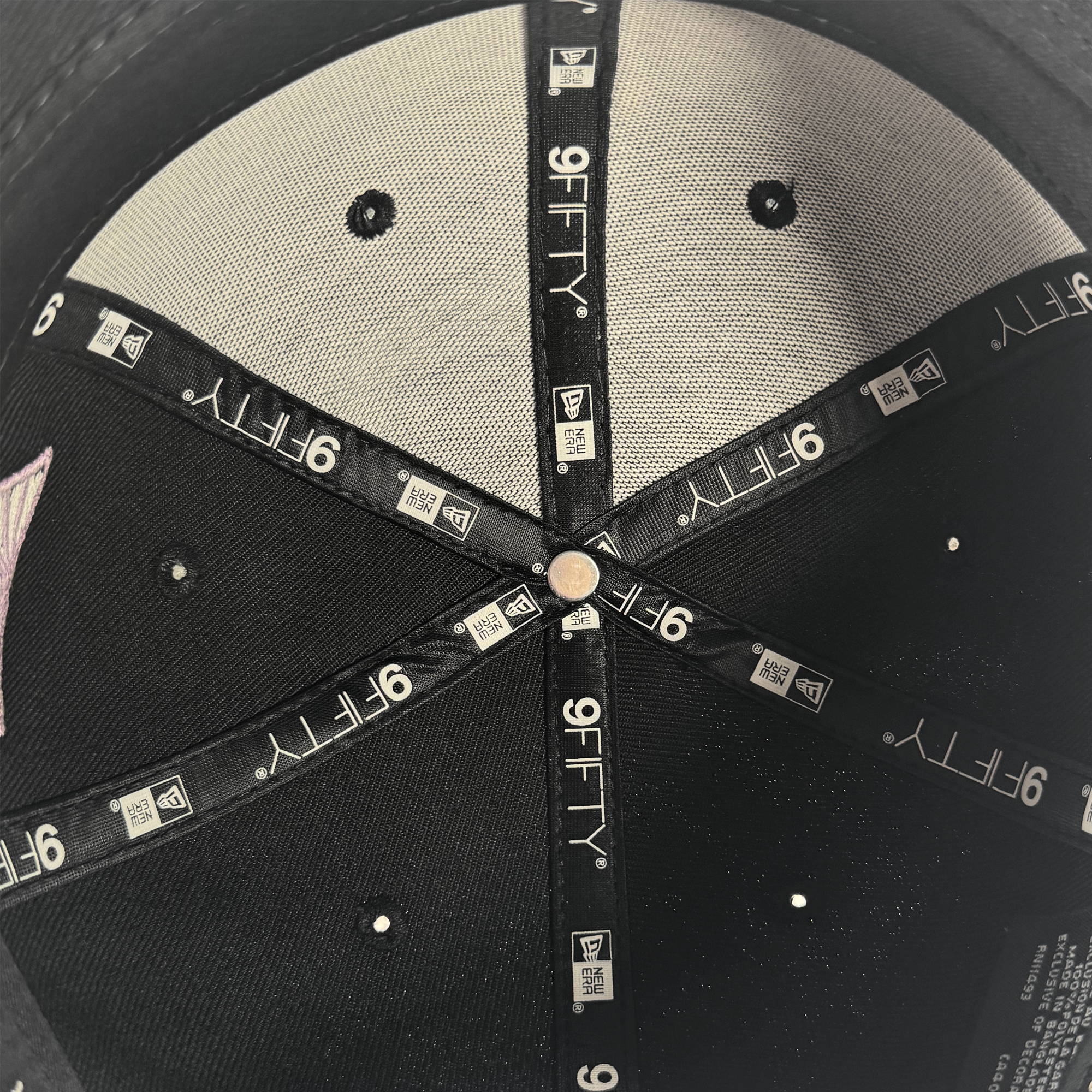 Close-up of the inside top of a black GSV WNBA 9FIFTY Snapback by GSV, featuring stitched panels, a metal center button, and black fabric strips with white “9FIFTY” and GSV logos. The label is visible on the right.
