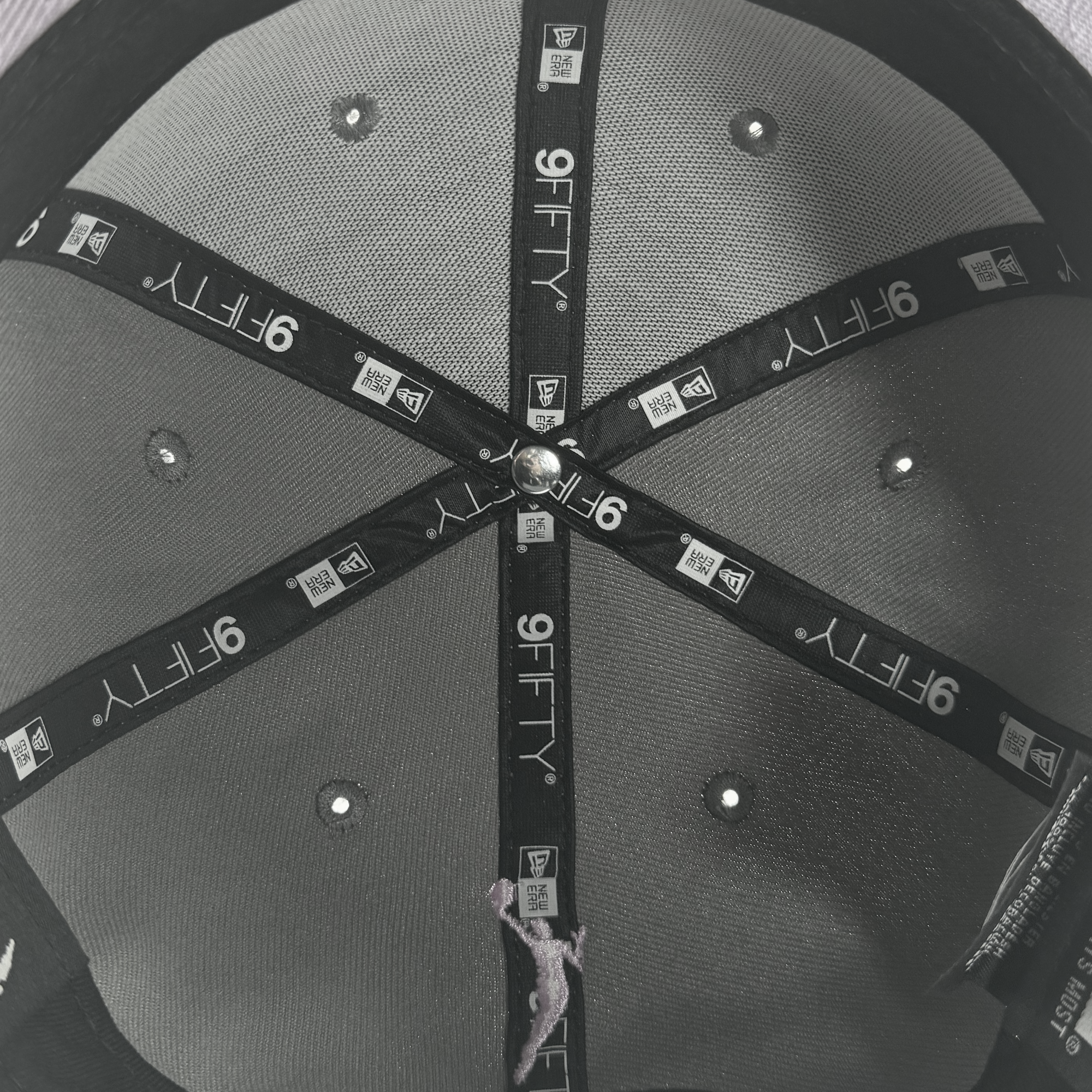 Close-up of the GSV Wordmark 9FIFTY Snapback: features grey and black panels, metallic vents, and branded inner fabric strips with "9FIFTY" and "NE" logos—a sleek style from GSV for Golden State Valkyries fans.