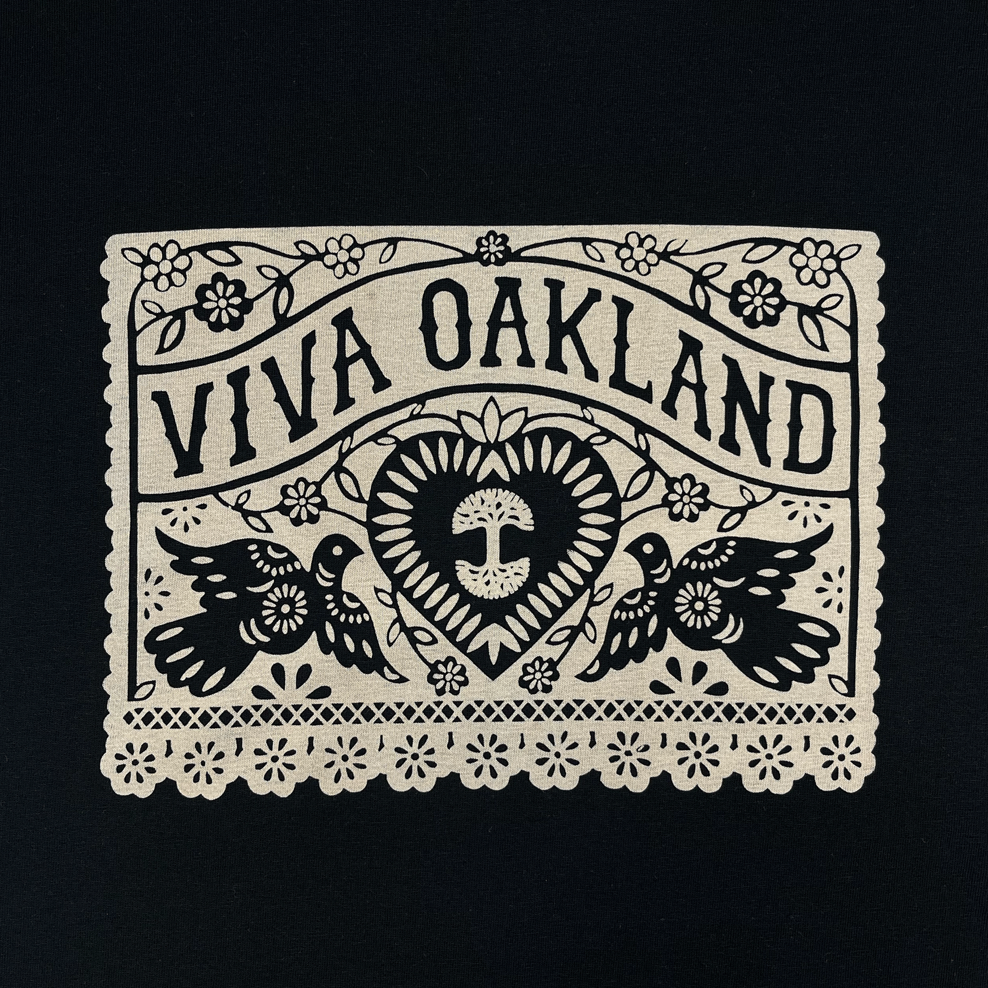 Close-up of intricate lace gold Viva Oakland graphic on the front chest of a black t-shirt.
