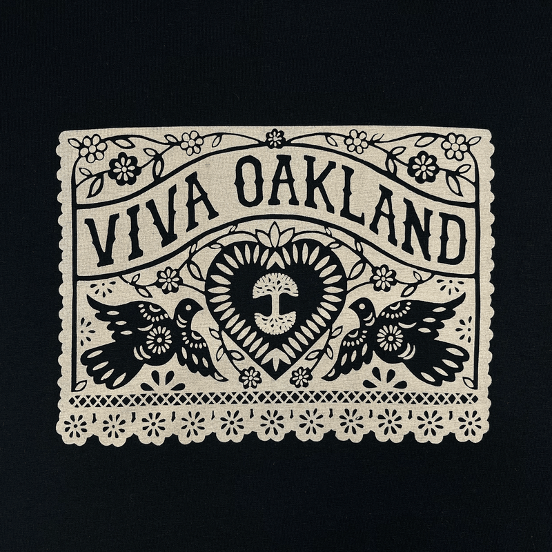 Close-up of intricate lace gold Viva Oakland graphic on the front chest of a black t-shirt.