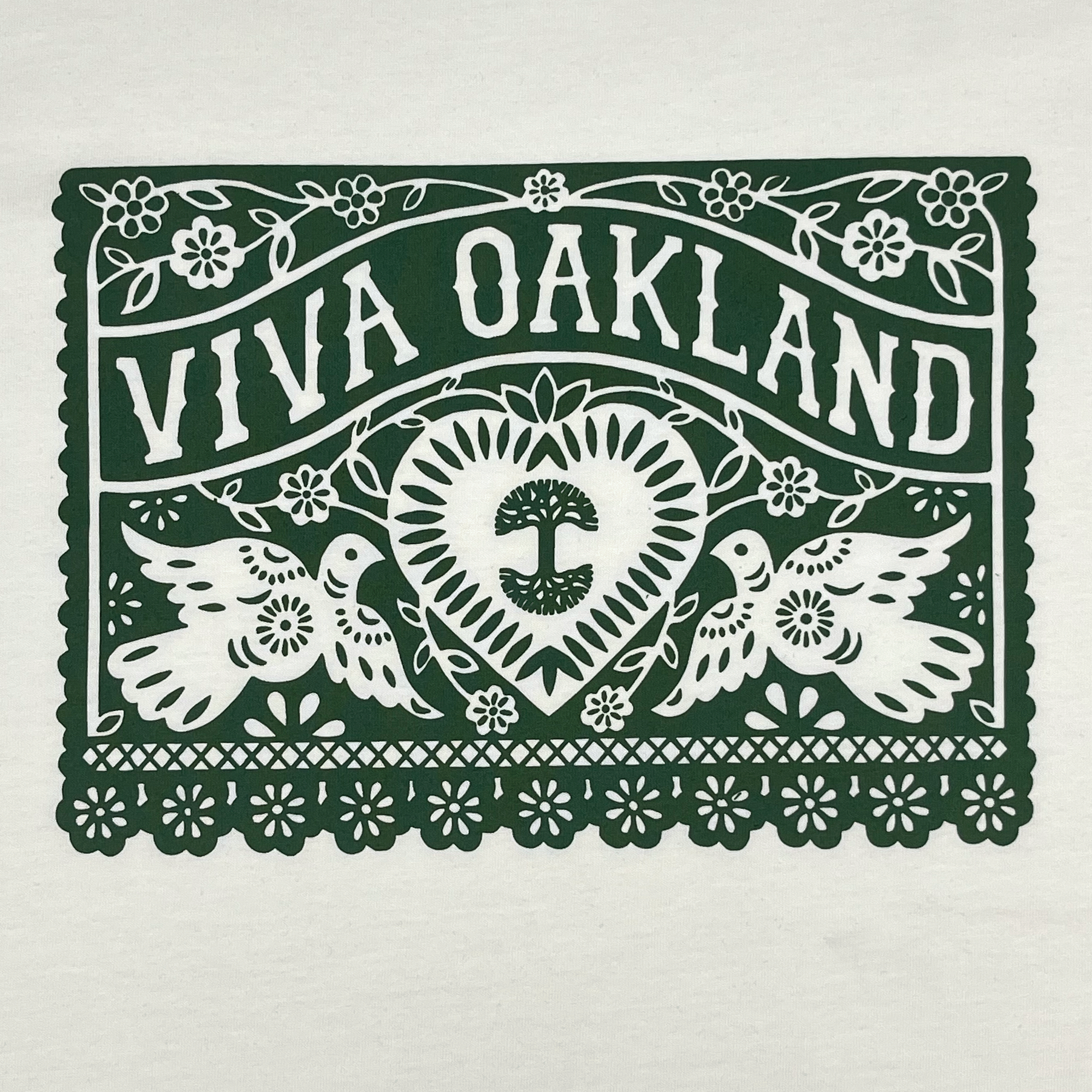 The Viva Oakland Tee by Oaklandish features a decorative design with the text "VIVA OAKLAND" in bold letters at the top. Below it, two birds flank a heart containing a tree emblem. The design includes intricate floral patterns and a scalloped border, all printed in dark green on a white background on this 100% cotton classic fit t-shirt.