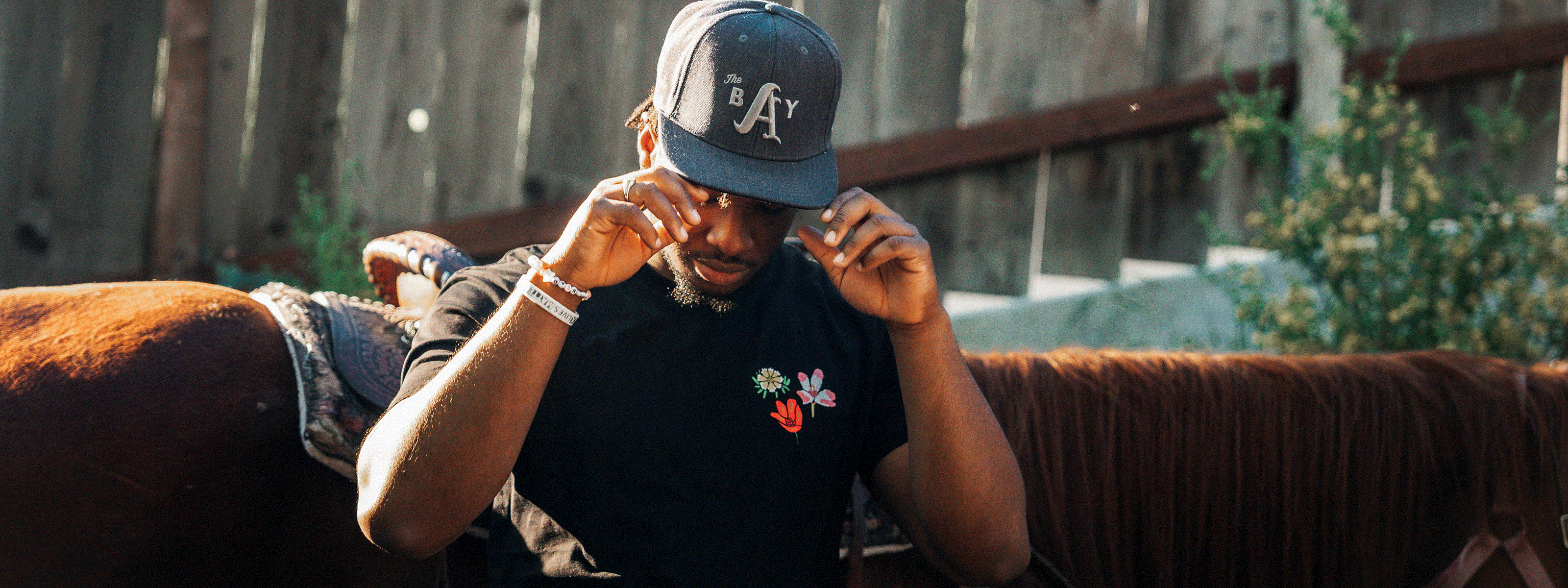 Model wearing The Bay Collection snapback by DOC and Wildflower tee in black.