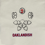 Close-up of Oaklandish worldwide graphic on the left chest wear side of a natural cotton-color t-shirt.
