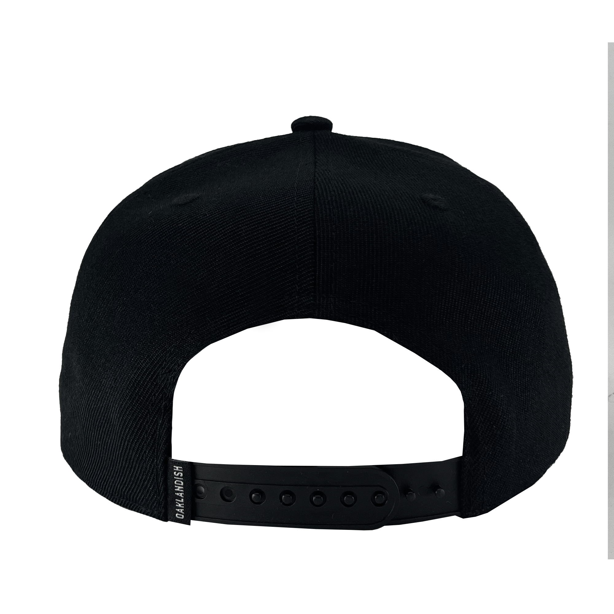 A rear view of the WPBA Snapback baseball cap by Oaklandish showcases its adjustable snapback closure with a combination of small and large holes for size customization. A small tag reading "GRANDMSH," which supports the empowerment of women in sports, is attached to the left side. The cap is black and plain, free from any additional designs.