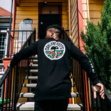 Man climbing the front stairs of Oakland house wearing a black long sleeve t-shirt with full-color circle Roots SC logo on the back.