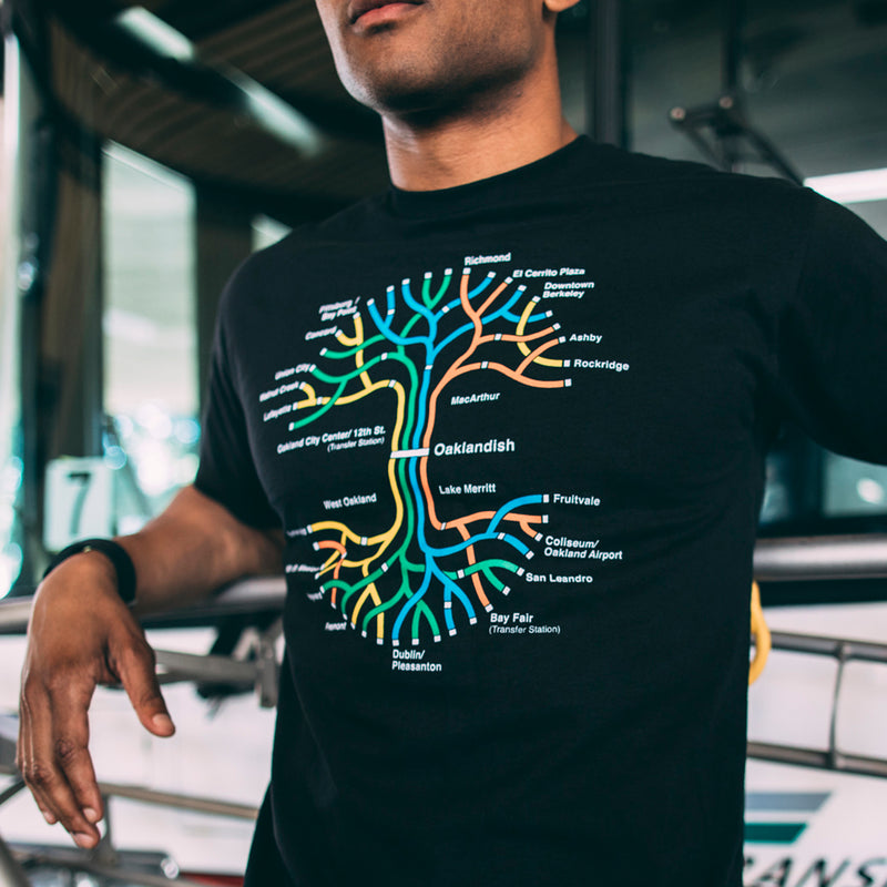 Man, chin to the waist, wearing a black t-shirt with a full-color BART transit map in the shape of the Oaklandish tree logo.