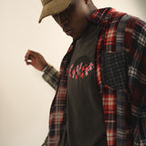 Man wearing a black t-shirt with a bear and flower design created by artist Ant Bankxin with plaid jacket and hand in the air.