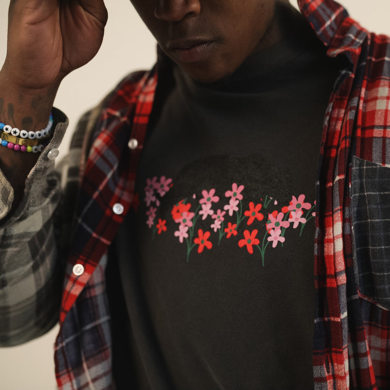 Close-up of a man wearing a black t-shirt with a bear and flower design created by artist Ant Bankxin with a plaid jacket.