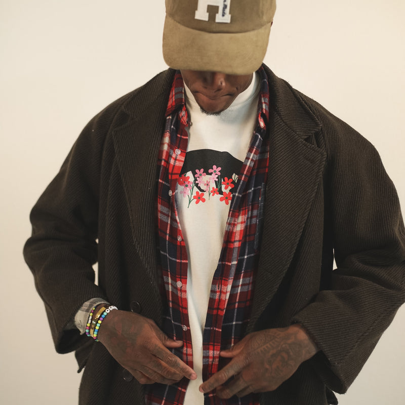 Man wearing a creme t-shirt with bear and flower design created by artist Ant Bankxin with his hands at his waist.