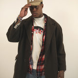 Man wearing a creme t-shirt with bear and flower design created by artist Ant Bankxin with his hands holding the bill of his cap.