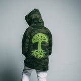 Kid back facing the camera wearing a green camo youth hoodie with large green Oaklandish tree logo. 