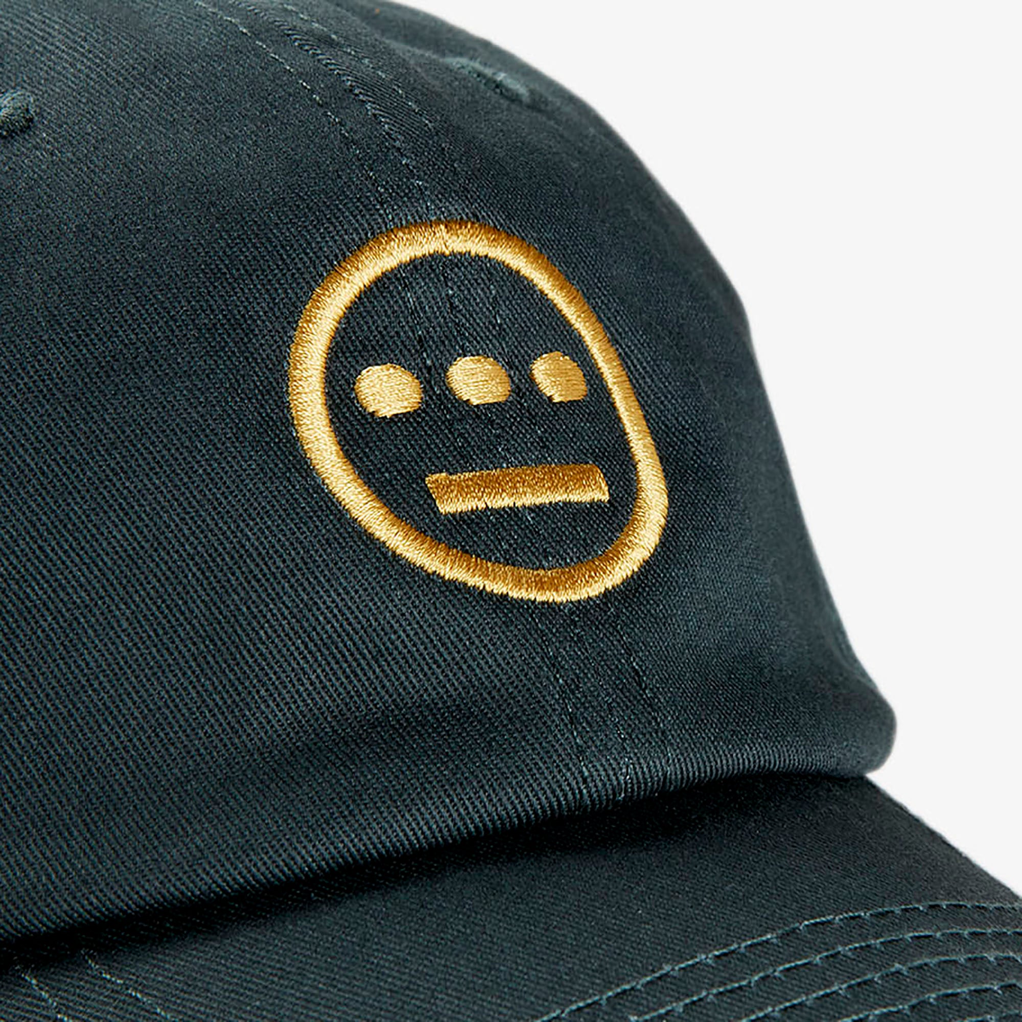 Close up of yellow embroidered Hiero hip-hop crew logo on crown of a forest green dad cap.