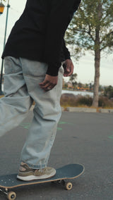 Man riding a skate board wearking long sleeve t-shirt designed by artist Jet Martinez.