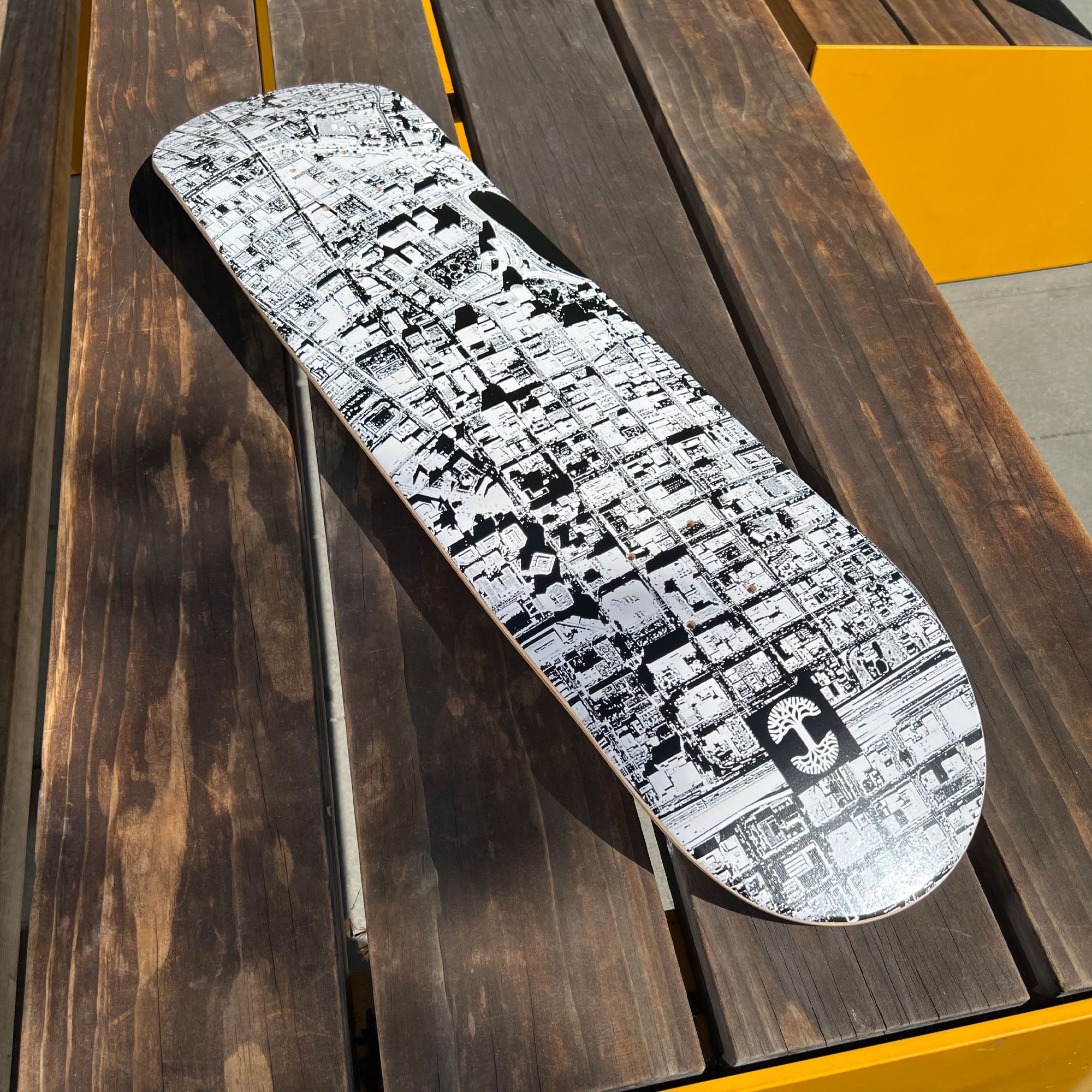 Black & white skateboard deck with an aerial image of Oakland and Lake Merritt on a wooden deck.
