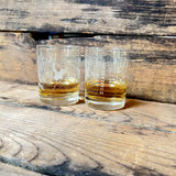 Pair of whisky tumblers with an aerial map of Oakland and Oaklandish wordmark on wooden bench