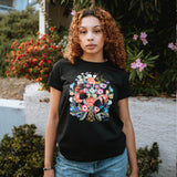 Woman wearing a black t-shirt with a flower & bird graphic by artist Jet Martinez.