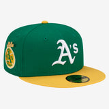 Green cap with Oakland As logo on crown, yellow bill and 1973 World Series patch and yellow cursive New Era logo on the side.