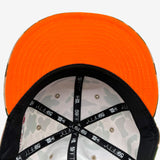 The bright neon orange underside of the bill on a fitted cap with a view of the inside of the crown with New Era 5950 taping.