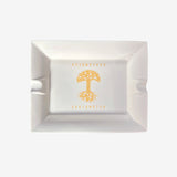 White ceramic ashtray with yellow Oaklandish tree logo and wordmark in the center.